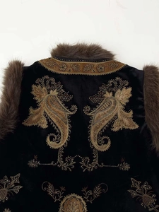 Detailed close-up of intricate gold paisley embroidery and brown faux fur trim on a velvet vest