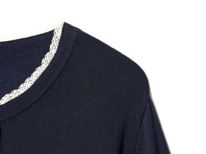 Detailed close-up of navy knit cardigan featuring white lace trim on the round neckline