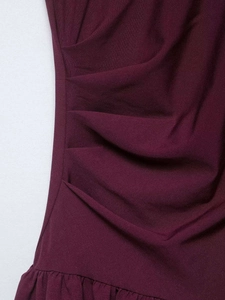 Vue détaillée de la robe bordeaux montrant les plis latéraux et la texture des volants