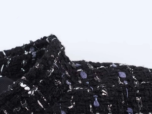 Detailed close-up of black and purple tweed fabric with metallic silver thread textures