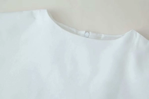 Detailed view of white cotton-linen dress with round neck and invisible back zipper