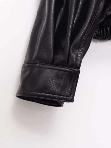 Detailed macro view of black faux leather jacket cuff with precise stitching and fine texture