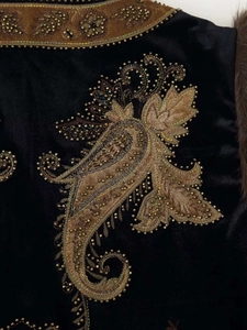 Close-up of vintage velvet vest featuring gold paisley embroidery and beaded details