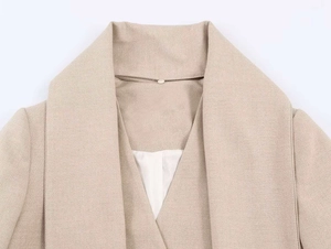 Dettaglio del risvolto largo e del tessuto twill strutturato su questo blazer beige