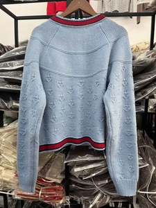 Vue détaillée du dos d'un cardigan en tricot bleu clair avec des bordures rayées rouge et bleu