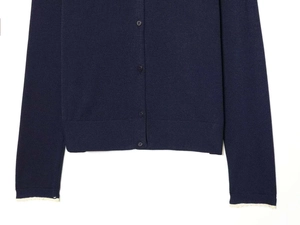 Detail of navy knit cardigan featuring delicate white lace cuffs and ribbed texture