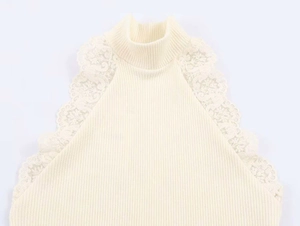Dettaglio del bordo in pizzo floreale sul top in maglia a coste color crema senza maniche