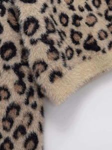 Close-up of soft leopard print knit fabric with detailed stitching and plush texture