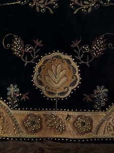Detailed embroidery and golden beadwork on a velvet vest with soft brown faux fur trim