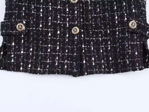 Detail of tweed blazer fabric with black blue weave and decorative gold buttons