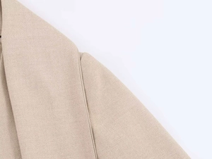 Dettaglio del collo a sciarpa del blazer beige con tessuto intrecciato e cuciture fini