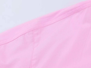 Close-up of pink poplin shirt fabric featuring precise double-needle stitching and seams