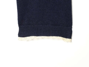 Detailed view of dark blue knit fabric featuring delicate white lace trim on the hem