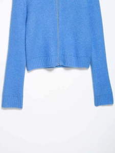 Close-up of blue knit sweater showing ribbed cuffs, silver zipper and soft fuzzy texture
