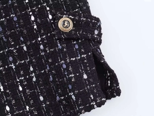 Close-up of metallic textured tweed blazer with a golden lion crest button detail