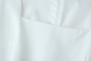 Macro shot of white dress square neckline featuring a concealed back zipper closure