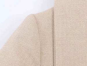 Dettaglio spalla e risvolto del blazer in lana a spina di pesce in classico beige albicocca