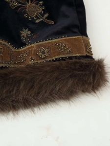 Close-up of vintage velvet vest with floral embroidery, gold beads and faux fur trim
