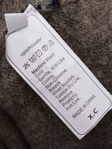 Close-up of garment care label showing 100% polyester material and washing instructions