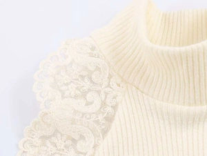 Dettaglio della spalla in maglia con ricamo in pizzo floreale e design a collo alto