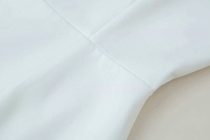 Close-up of clean white fabric texture and fine stitching detail on summer dress