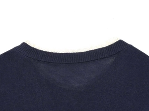 Close-up detail of navy knit sweater featuring ribbed neckline and delicate white lace trim