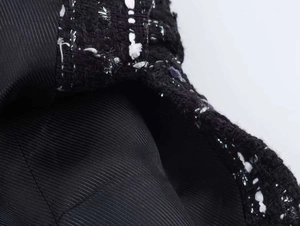 Detailed macro view of black tweed blazer fabric with purple and silver metallic threads