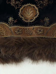 Close-up of golden embroidery and beadwork on black velvet vest with faux fur trim