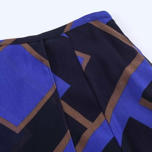 Detailed view of geometric print midi skirt fabric with blue and brown patchwork patterns