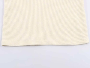 Dettaglio della trama a costine e cucitura dell'orlo sulla maglia crema senza maniche