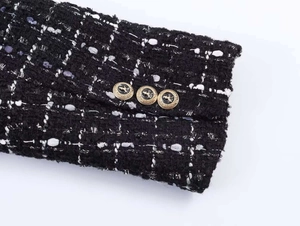 Detail of black tweed jacket cuff featuring metallic fibers and lion crest gold buttons