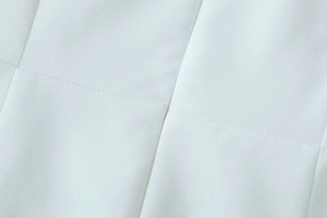 Macro detail of high-quality white fabric texture and precision stitching on the dress
