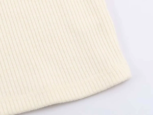 Dettaglio ravvicinato della trama a costine su un top a maglia senza maniche panna