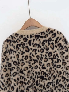 Detail view of leopard print knit sweater texture and neckline on wooden hanger
