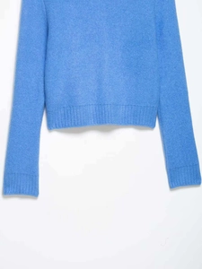 Close-up of sky blue knit sweater showing ribbed cuffs and soft wool fabric texture