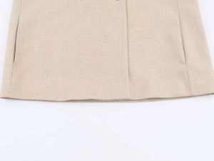 Dettaglio dell'orlo del blazer beige con tasca laterale e trama del tessuto testurizzato