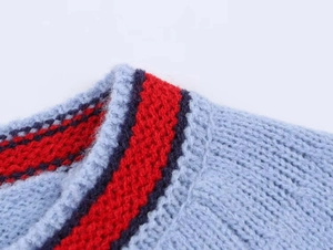 Vue macro d'un cardigan en maille bleue avec encolure à rayures contrastées rouge et bleu