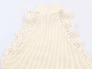 Dettaglio del top in maglia beige con collo a lupetto e bordo in pizzo sulle spalle