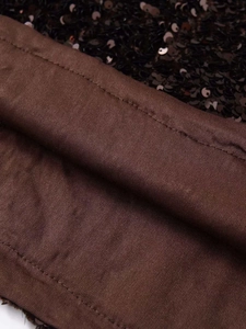 Macro shot of black sequins detailing and dark brown knitted lining on a stylish skirt