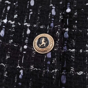 Close-up of black tweed blazer with metallic threads and a golden lion crest button