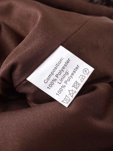 Detail showing the material care label on 100% polyester brown sequined skirt fabric