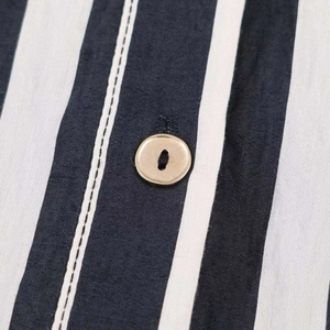 Macro shot of vertical striped fabric with a brown button and precision stitching