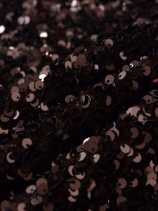 Macro shot of high-shine sequins on a black mini skirt with metallic reflective finish