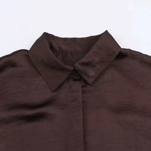 Close-up of the collared neckline and smooth satin fabric on a dark brown shirt