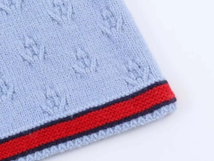 Détail d'un cardigan en maille bleu clair avec motifs texturés et rayures contrastées