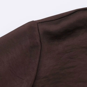 Close-up of the smooth dark brown satin fabric texture and precise stitching on the shoulder