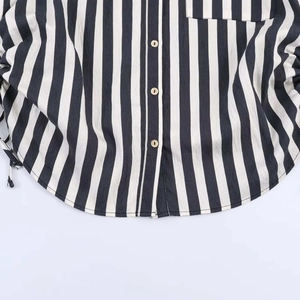Detailed close-up of striped shirt featuring wooden buttons and side drawstring design