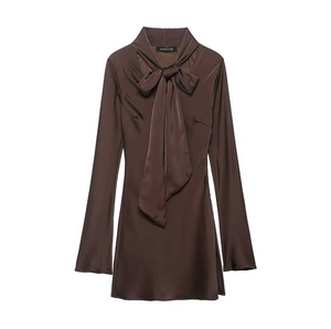 Détail d'une robe en satin marron avec un grand nœud au col et texture lisse