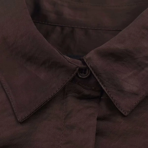 Detail of the sharp collar and resin button on a dark brown satin texture shirt