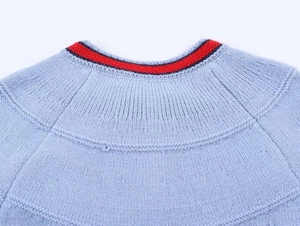 Détail du col en maille côtelée avec des rayures contrastées rouges et bleu marine
